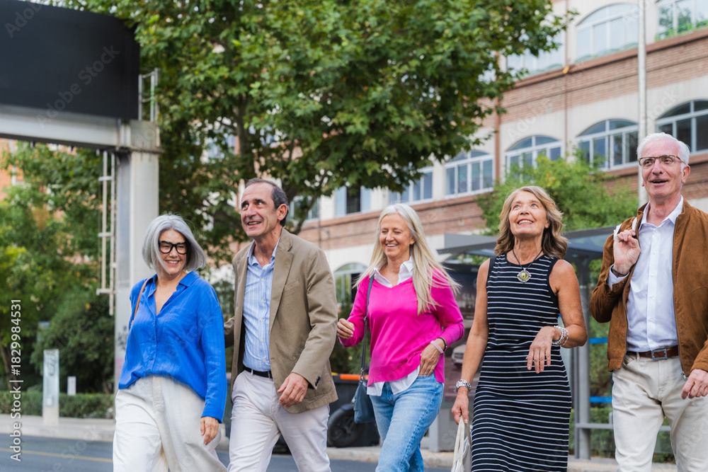 Obraz premium Mature friends walking together enjoying urban street lifestyle