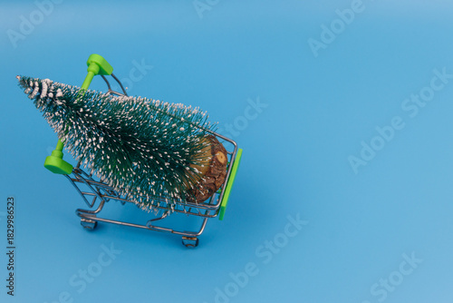 Wallpaper Mural Shopping cart with Christmas tree on pastel blue background. Christmas shopping concept Torontodigital.ca