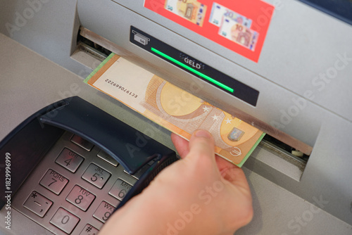 Tableau sur toile Hand withdrawing euro banknote from an ATM machine in Germany