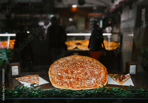 Fresh Italian pizza displayed behind glass inside a traditional pizzeria in Italy.