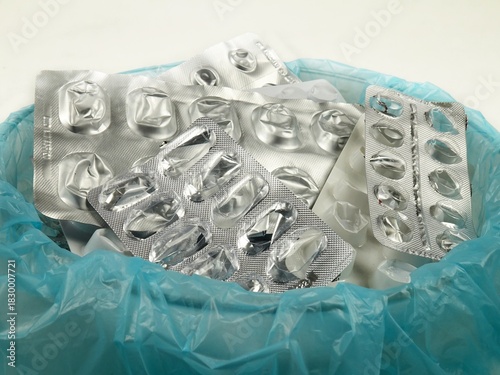 Heap of empty pill blister packs in a special container for disposal,  used pill pack blisters, side view. Treatment and medication concept