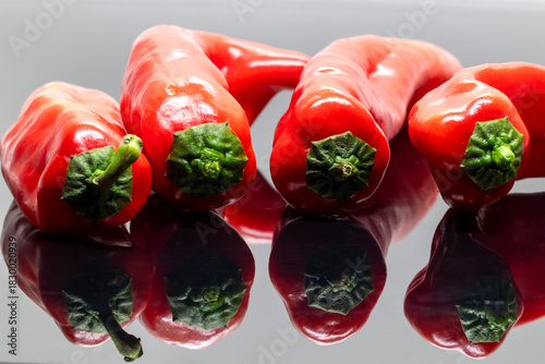 Red capsicums, isolated on a reflected background.