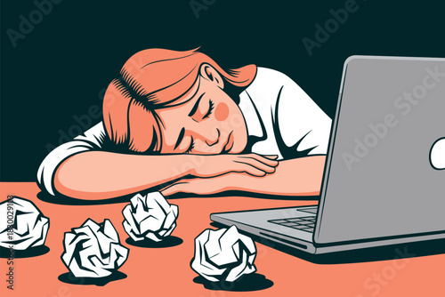 A person rests their head on their arms on a desk next to a laptop and crumpled paper balls.