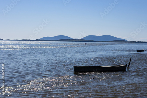 Small wooden boat moored in Narta Lagoon, Albania. Beautiful coastal landscape with a lake and distant mountains