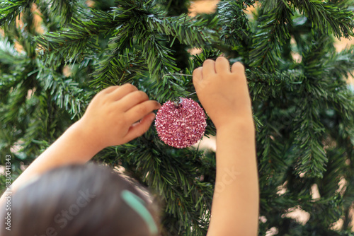 Primer plano de manos de niña colocando un adorno rosado brillante