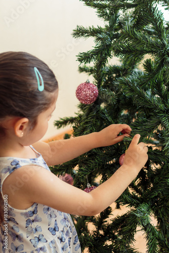 Niña tocando las ramas del árbol de Navidad