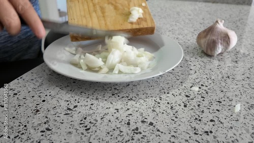 After chopping the onion on a wooden board, it is transferred to a white plate.