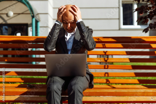 Disappointed man lost the bet. An upset person checks the betting results on a laptop outdoors in a park. Online betting
