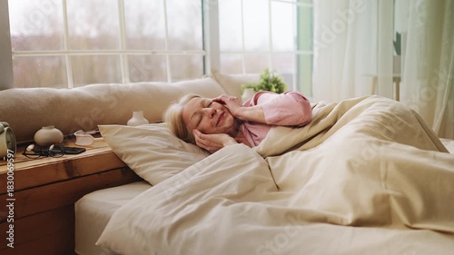 Senior woman waking up in bed with strong migraine, unhealthy sleep, insomnia