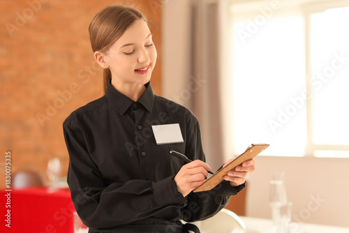 Young waitress writing on c...