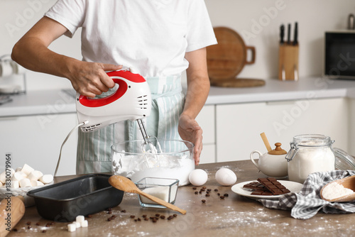 Φωτογραφία Woman whipping egg albumen with mixer at table in kitchen