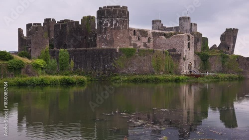 Panning view of the medieval ruins of Caerphilly Castle reflected in its moat, Wales.