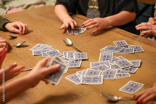 Group of people playing the fun, popular and competitive card game spoons on the dining room table. 