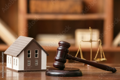 Judge's gavel with house figure on table in office, closeup