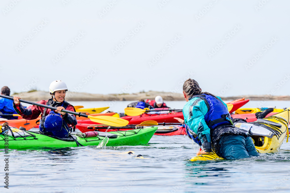 Fototapeta premium Two female sea kayakers practice rescue techniques during a guide training program on Georgian Bay, Ontario, Canada. room for text
