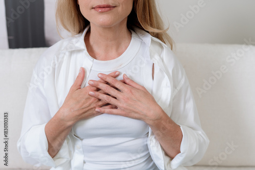 Calm mature woman practicing meditation for mental health and stress relief at home