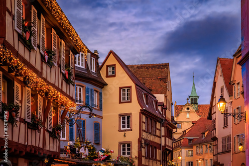 Fototapeta Naklejka Na Ścianę i Meble -  Christmas decorations on half timbered houses in Colmar, France glow at sunset