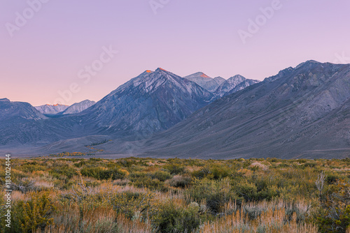 Photos Soft pink and purple alpenglow illuminates the highest summits of the Sierra Nevada at dusk, viewed across the sagebrush high desert along US-395 near Hot Creek, California
