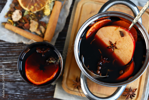 Homemade mulled wine in a ladle, spices, oranges and apples