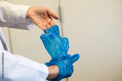 Doctor or Nurse Rolling Off Blue Barrier Glove, Focusing on Hand Hygiene Procedure.