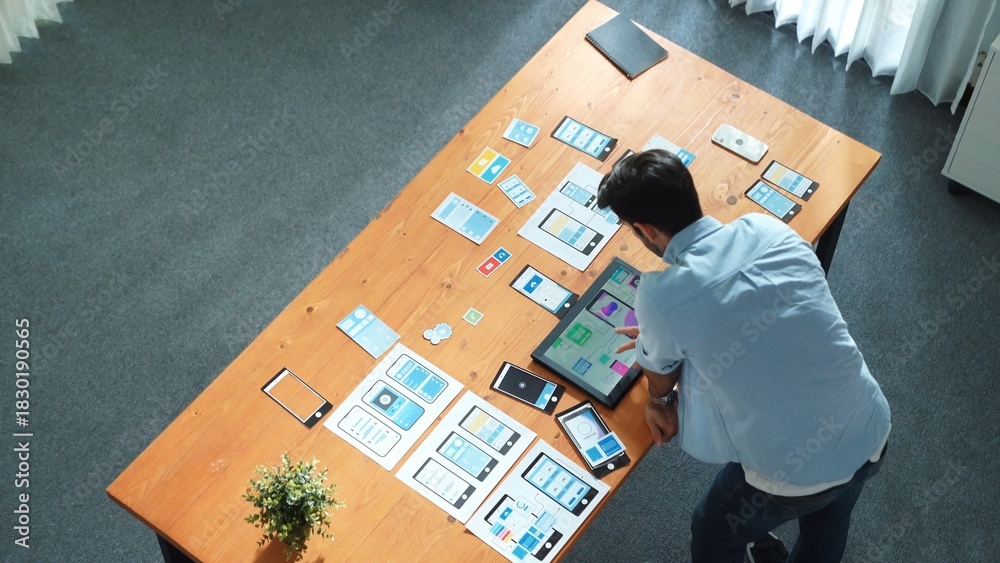 Naklejka premium Top view of skilled businessman looking at Ux Ui design in tablet while designing protocol or choosing wireframe interface. Caucasian smart front-end developer planning about UI design. Convocation.
