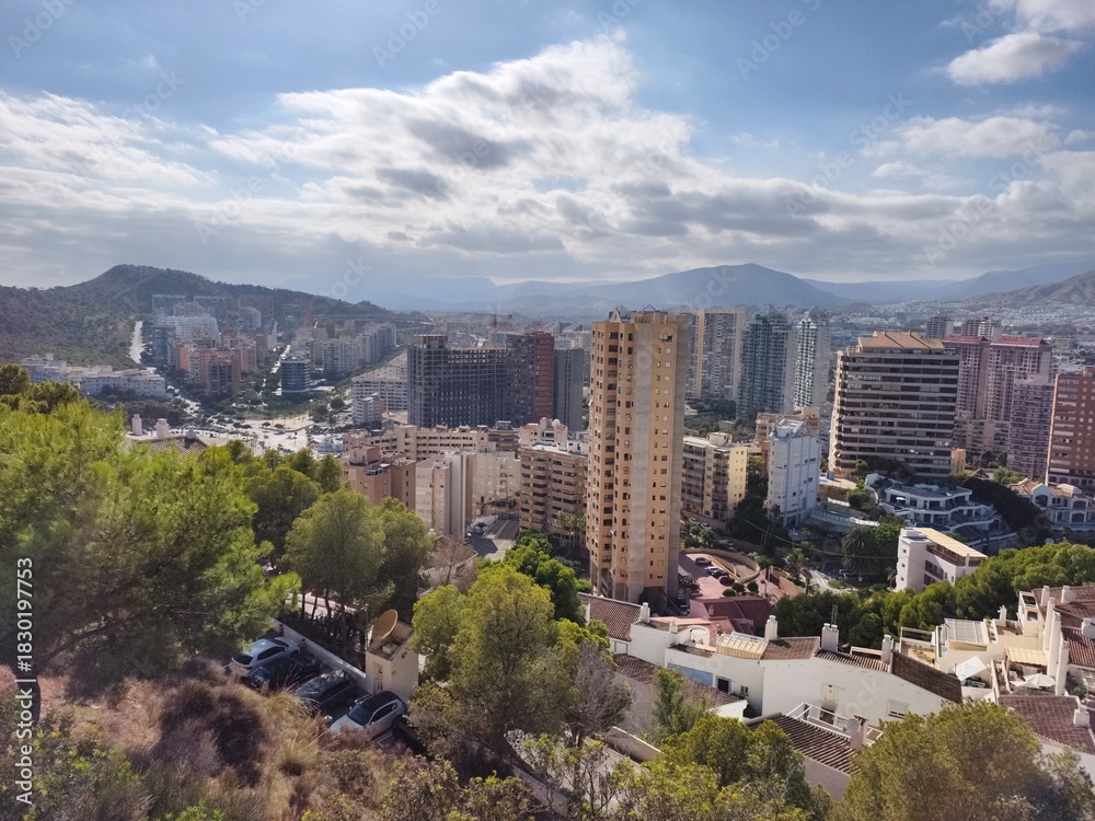 Obraz premium sunlit rooftops and distant horizon, urban hillside overlooking city skyline with mountain backdrop