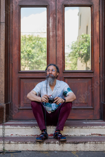 Man with vintage camera seen sitting on stairway