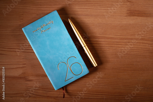 2026 planner and gold colored pen on wood background