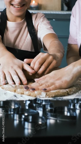 Vertical video. Teen girl rolls ginger cookie dough with guidance from her mother, enjoying a playful baking moment, slow motion