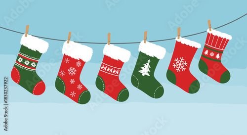 A festive display of six red and green Christmas stockings, adorned with winter patterns and furry cuffs, hanging on a clothesline against a light blue background.