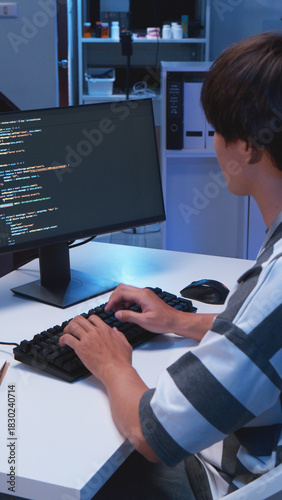 One young male Asian IT freelancer programmer and tech engineer working with computer keyboard, typing software codes for application development and website network system information data in room.