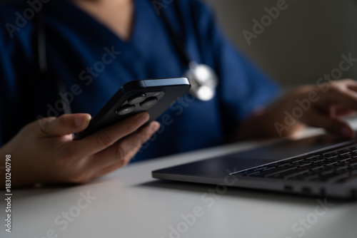 Nurse or doctor using phone and laptop in clinical setting, highlighting telehealth innovations, connected healthcare systems, and digital tools for efficient patient care and online treatment access.