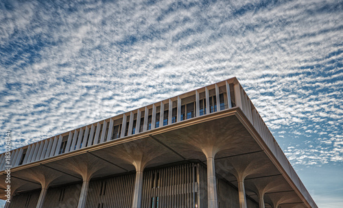 White and Blue Checkered Sky Above a Square Building Roofline.
