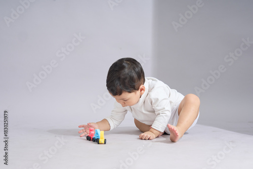 The child kneels while pushing or adjusting a toy car with focused attention.