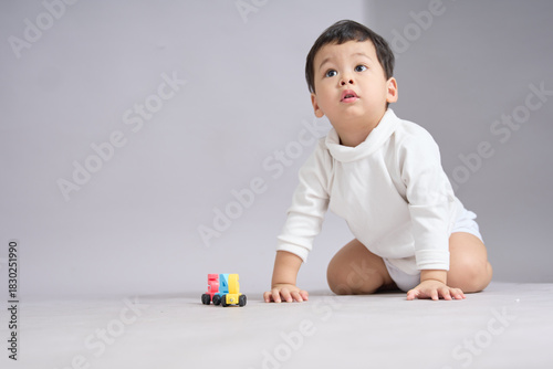 The child sits back on heels, hands resting near a neat row of colorful toy cars.