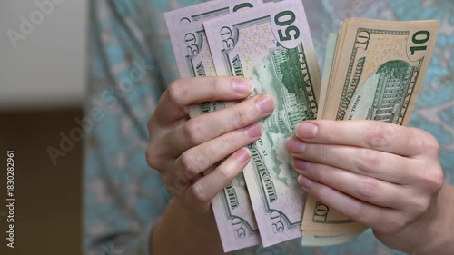 In a cozy home, a housewife organizes and counts her cash for daily needs. Each bill is carefully handled as she plans for the day ahead, ensuring everything is in order.