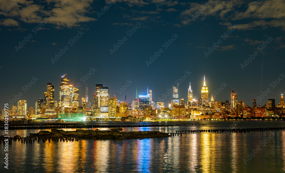 Naklejka premium The Manhattan skyline in night New York city at dusk. Iconic city view of New York in night. NY night towers above the Hudson. NYC night skyscrapers against the sky. Famous New York panorama.