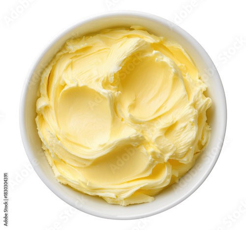 Soft yellow butter with creamy swirled texture in white ceramic bowl top view, isolated on transparent background