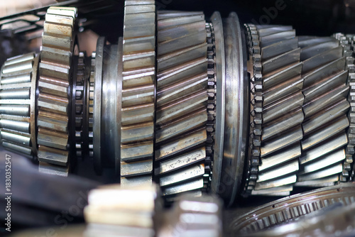 Close-up of a disassembled automotive transmission main shaft, featuring a series of stacked helical gears and synchronization rings, symbolizing complex mechanical engineering and vehicle repair.