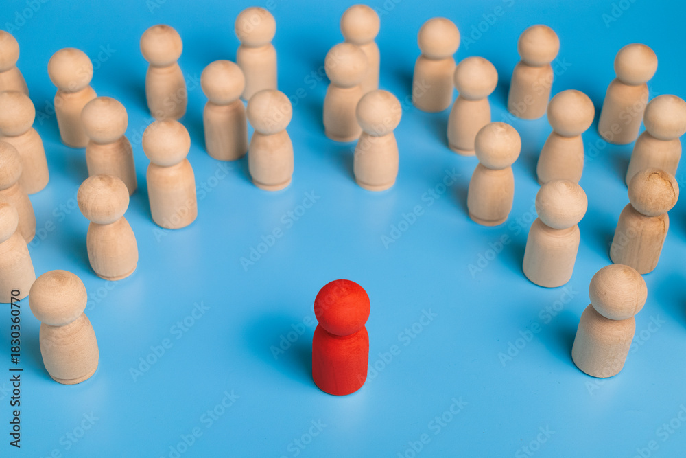 Obraz premium red wooden figure stand to the wooden group crowd. isolated on blue background. leadership and teamwork concept