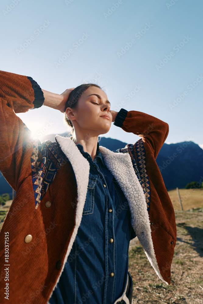 Naklejka premium Woman, portrait and outdoors with sunlight and jacket near mountains, enjoying nature and travel. Female model in denim shirt with closed eyes, relaxed pose in countryside golden hour.