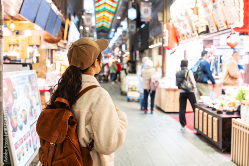 Young female tourist looking for food and souvenirs at the popular Nishiki Market in Osaka
