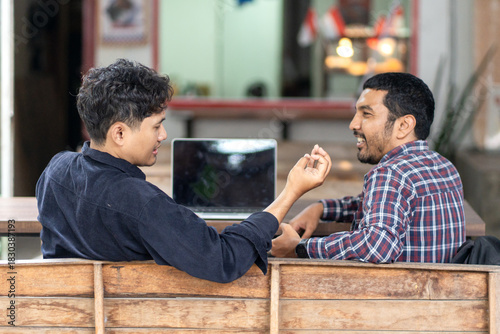 Two men working together in an outdoor cafe space