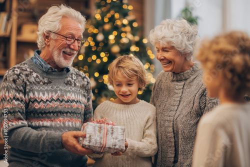 A family of grandparents and grandchildren exchange gifts next to the Christmas tree