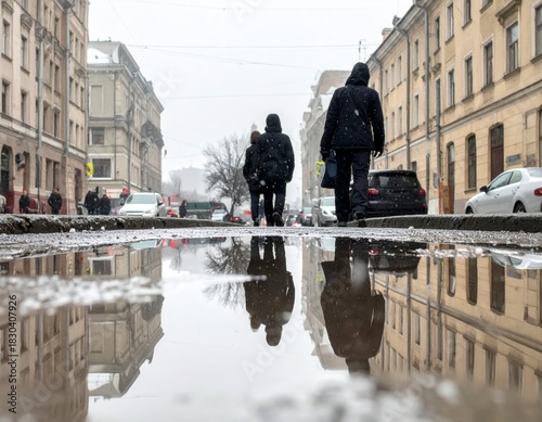 Urban winter street scene with pedestrians walking through snow and reflections in a large puddle