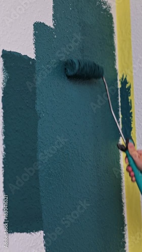 Wall painting process showcasing a hand rolling paint on a textured surface, with gradual zoom emphasizing color application and technique