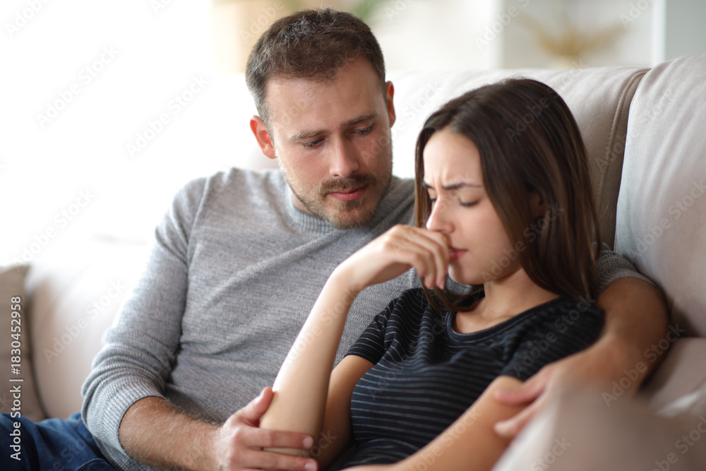 Obraz premium Man comforting sad woman on a couch at home