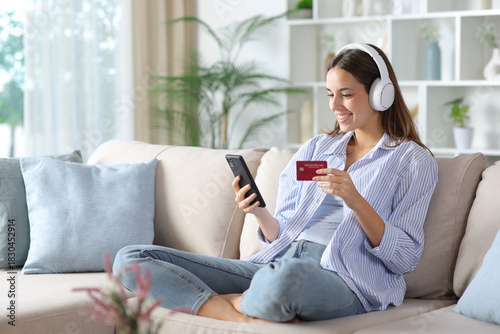 Happy woman in blue wearing headphone buying online