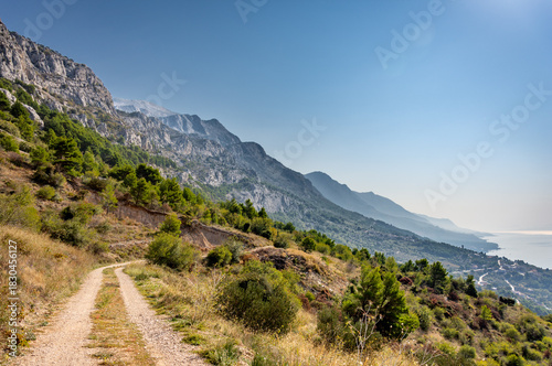 Fototapeta Naklejka Na Ścianę i Meble -  Croatia's Adriatic coast in Dalmatia on the Makarska Riviera, with the Biokovo Mountains and forests in the background. Golden hour with beautiful beaches and a rocky coastline.