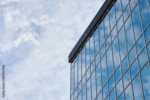 Glass facade of modern office building with large windows reflecting sky. Contemporary architectural design